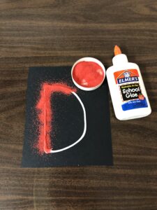 Sprinkle sand on glue to practice letters