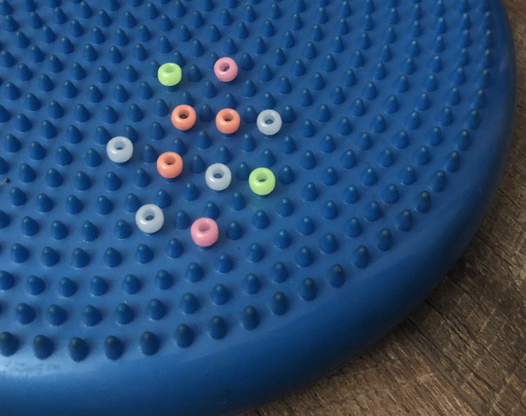 Have child place pony beads on nubs of a wobble disc for fine motor coordination.