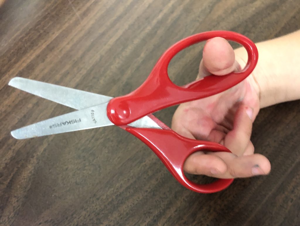 Flip scissors around to encourage side hand separation with only 2 fingers fitting in the smaller hole.