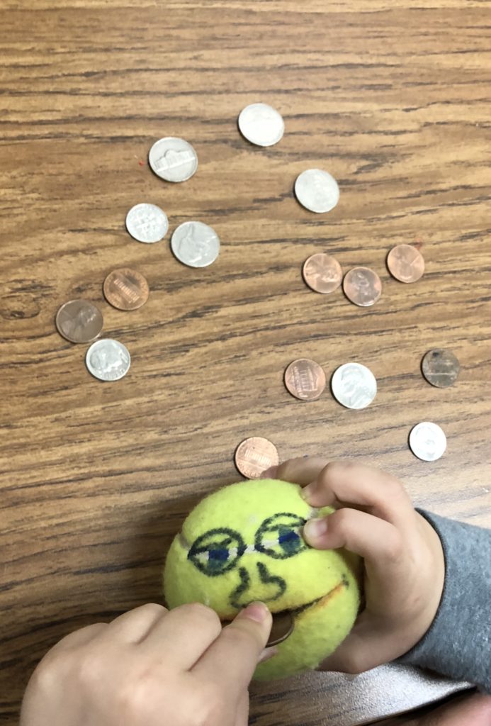 WooTherapy likes using a tennis ball with a slit a smiley face to feed coins to work on bilateral coordination and fine motor skills.