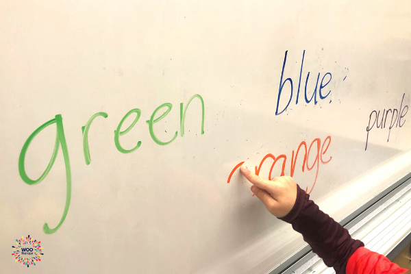 A child using a pointer finger to trace and erase marker off a white board.